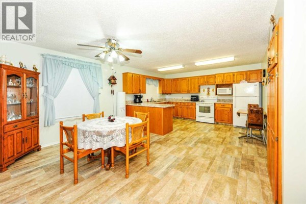 Kitchen and dining area with a round table, wooden cabinets, and beige floor. - 4912 56 Avenue, Ryley