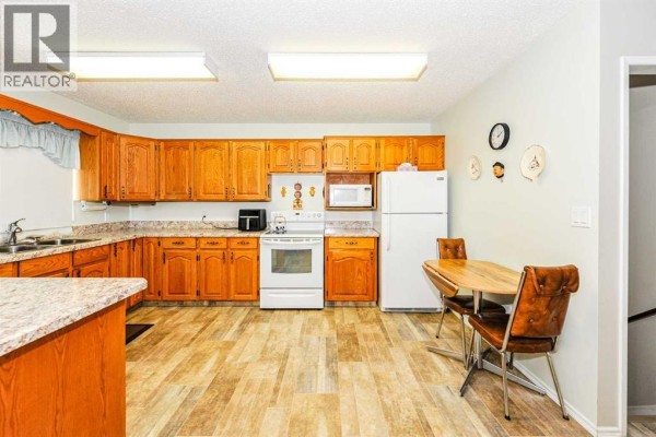 Kitchen with ample oak cabinets, white appliances, and a small dining set. - 4912 56 Avenue, Ryley