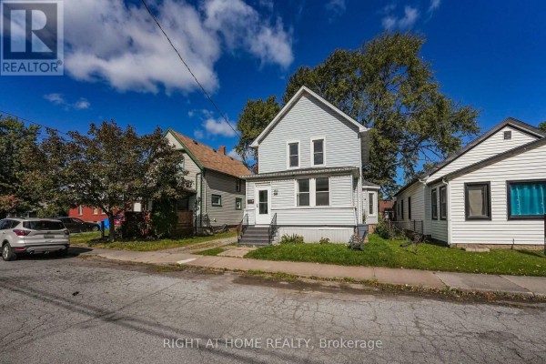 A hallway with a wooden staircase, hardwood floors, and doorways to other rooms. - 4919 Huron Street, Niagara Falls