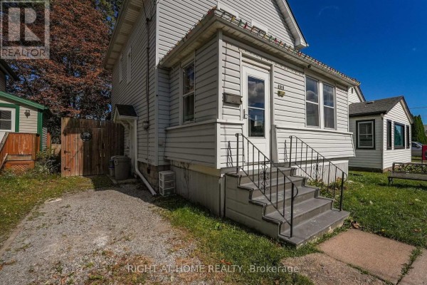 A dark wood staircase and shelving unit next to a brown front door with a glass pane. - 4919 Huron Street, Niagara Falls