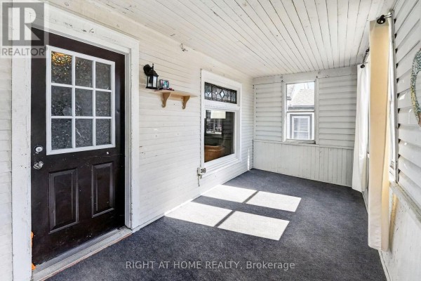 A bedroom with a colorful quilt, ceiling fan, dresser, and two windows with patterned curtains. - 4919 Huron Street, Niagara Falls