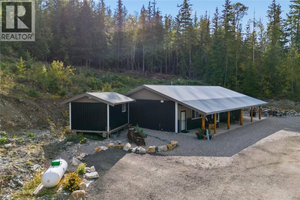 Outdoor patio area with four chairs, a small table, and a metal fire pit on a gravel base. - 4920 Ivy Road, Eagle Bay