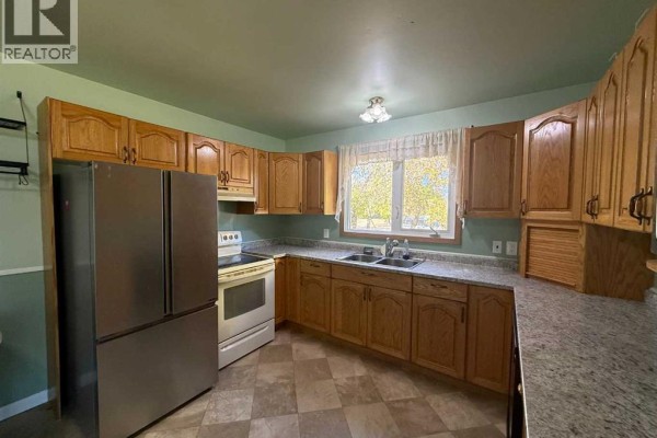 Kitchen with light wood cabinets, stainless steel refrigerator, white stove, and checkered floor. - 4925 52 Avenue, Eaglesham