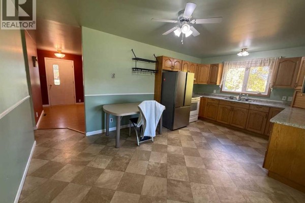 Kitchen with light wood cabinets, dining table, and view into a hallway. - 4925 52 Avenue, Eaglesham