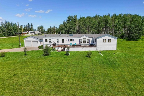 Front view of a white mobile home with a white garage and a green and white barn in a rural setting. - 49327 Rge Rd 53, Rural Brazeau County