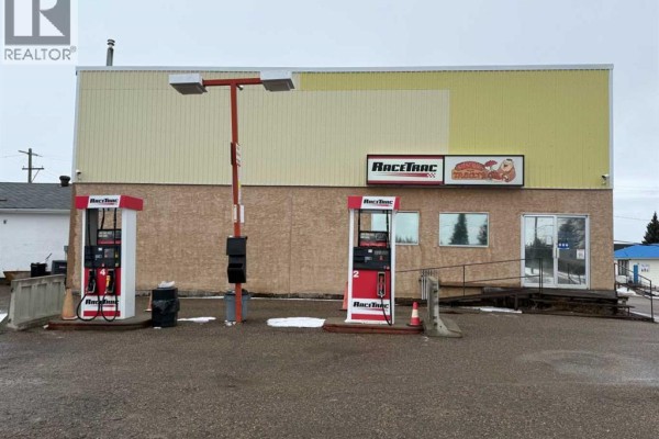 Side view of the commercial building showing two red gas pumps with lighting. - 4934 50 Avenue, Kitscoty