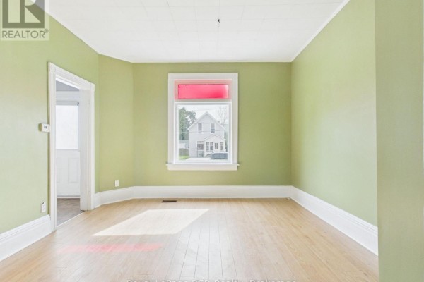 Empty room with light green walls, white trim, and a window with red accent. - 494 16th Street W, Owen Sound