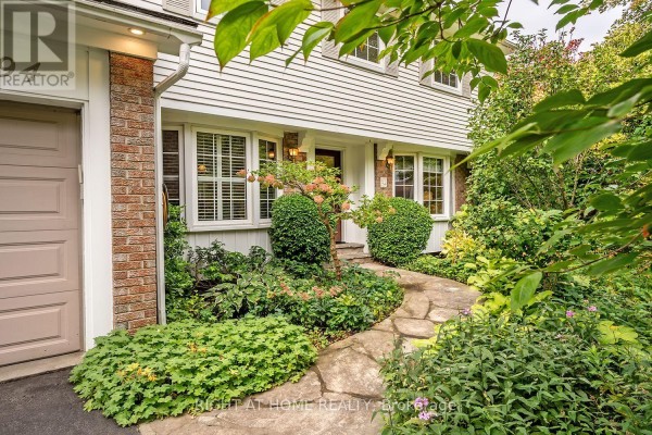 Stone pathway leading to the front entrance of a home with a garage and landscaped garden beds. - 494 Dorland Road, Oakville