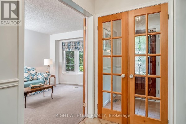 View from hallway into a living room with floral sofa and double glass doors leading to another room. - 494 Dorland Road, Oakville