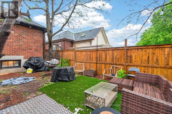 Backyard with artificial turf, wicker furniture, hanging chair, fire pit, and fence - 494 Highbury Avenue N London East