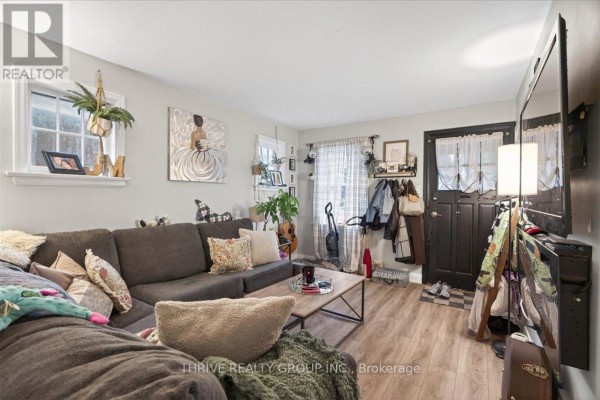 Living room with a sectional sofa, coat rack by the door, and wall art. - 494 Highbury Avenue N, London East