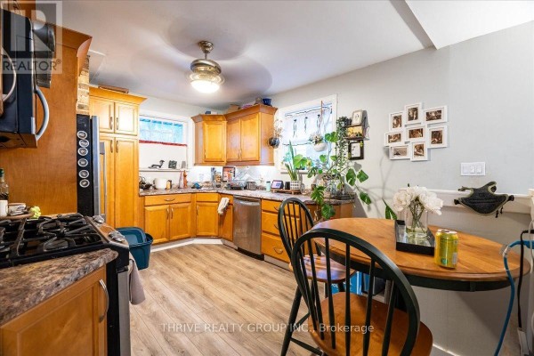 Kitchen with wood cabinets, stainless steel dishwasher, gas range, and dining table - 494 Highbury Avenue N London East