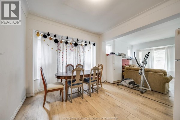 A living room with a brown sofa, a large TV, and white curtains. - 494 Rankin, Windsor