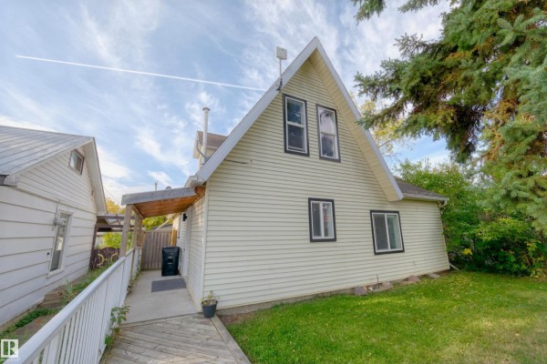 Rear exterior of a light yellow house with a peaked roof, multiple windows, and a covered walkway. - 4947 49 Avenue, Barrhead