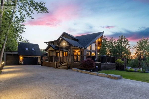 Front entrance of a wood-sided house with dark trim, wooden deck, and prominent rooflines. - 4949 Lyon's Parkway, Niagara Falls