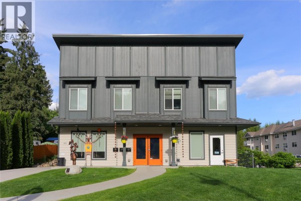 Front view of a two-story commercial building with beige lower level and grey upper level. - 495 Columbia Street, Castlegar