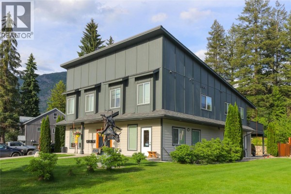 Side view of a three-story commercial building with grey metal siding and beige lower level. - 495 Columbia Street, Castlegar