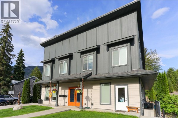 Close-up front view of a commercial building showing orange entrance doors and beige exterior walls. - 495 Columbia Street, Castlegar