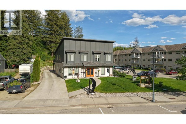 Panoramic aerial view of a town surrounded by lush green mountains and a river. - 495 Columbia Street Unit# 1, Castlegar