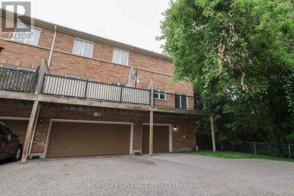 Front view of the brick townhouse with a large tree in the foreground. - 495 Mearns Avenue, Clarington