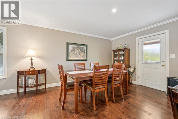 Dining room with a wooden table, six chairs, display cabinet, and hardwood floors. - 495190 Traverston Road, Markdale
