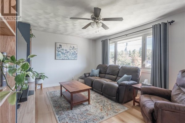 Living room with brown leather recliners, a sofa, a wooden coffee table, and a ceiling fan. - 4961 Coleen Avenue, Hanmer