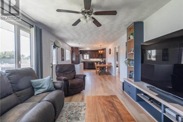 Living room with recliners, a view into the open-concept kitchen, and light wood floors. - 4961 Coleen Avenue, Hanmer