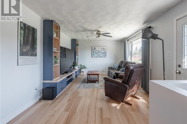 Living room with a TV unit, blue built-in shelving, a recliner, and a large window. - 4961 Coleen Avenue, Hanmer