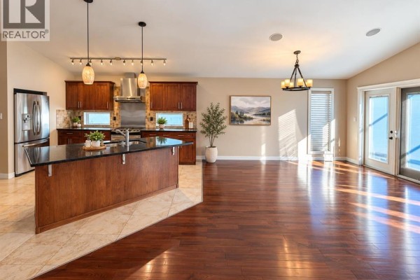 Open-concept living and kitchen area with dark wood floors and a large island. - 497 Edinburgh Road W, Lethbridge