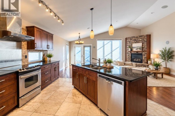 Kitchen with dark wood cabinetry, granite countertops, and a stainless steel appliance suite. - 497 Edinburgh Road W, Lethbridge