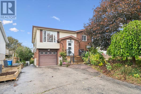 Side exterior view of the brick and vinyl house, showing the driveway and garage. - 497 Forfar Street E, Centre Wellington