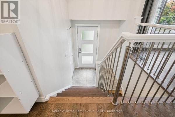 View looking down a staircase with hardwood floors and metal railings into an entryway. - 497 Forfar Street E, Centre Wellington