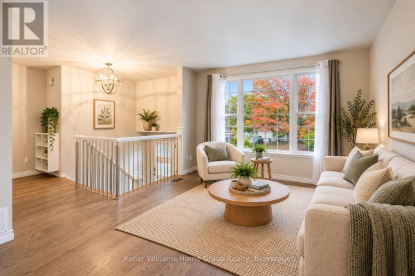 Living room with a sofa, chairs, coffee table, large window, and hardwood floors. - 497 Forfar Street E, Centre Wellington