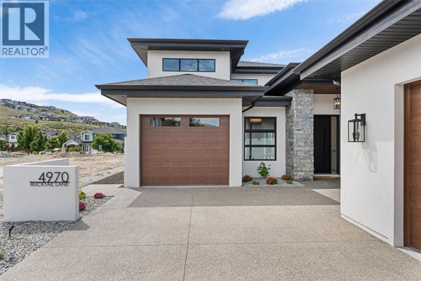 Close-up of the entrance featuring stone accents and landscaped front yard. - 4970 Bucktail Lane, Kelowna