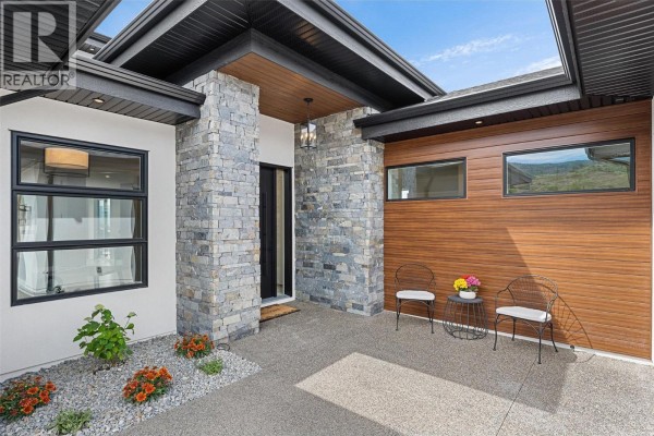 Covered entryway with stone pillars, wooden accents, and seating area. - 4970 Bucktail Lane, Kelowna