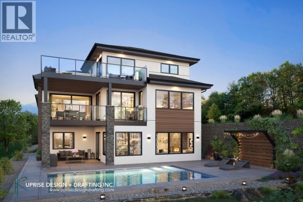 Side view of the house showcasing landscaping, stone wall, and large windows. - 4970 Bucktail Lane, Kelowna