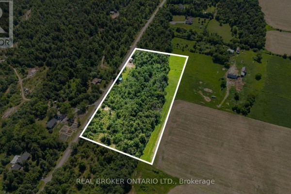 Aerial overview of the 4983 Stonecrest Road property showing 6.46 acres of land with surrounding fields and trees. - 4983 Stonecrest Road, Ottawa