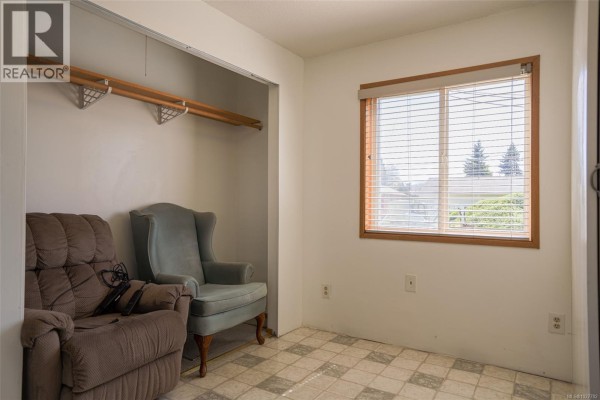 Kitchen with wood cabinetry, laminate countertops, white appliances, and checkered flooring. - 4987 Gertrude St, Port Alberni