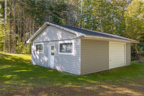 A detached grey garage with a white roll-up door and two windows on a grassy lawn. - 499 Ledge Road, Dufferin