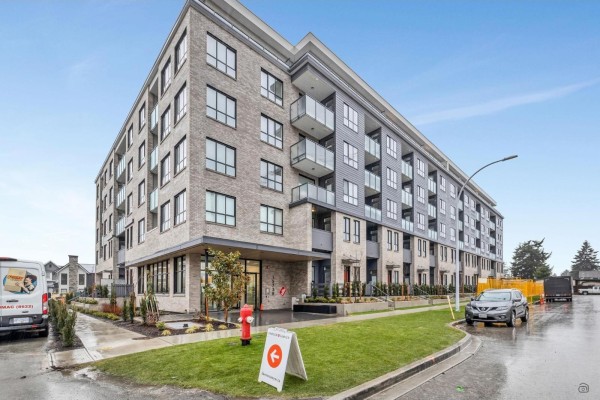 Street view of a brick and dark gray apartment building with balconies and landscaping. - 4f 15738 85 Avenue, Surrey
