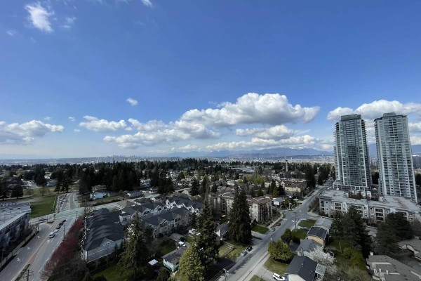 View from balcony showing cityscape, mountains, and two tall apartment buildings. - 4xx 13359 Old Yale Rd, Surrey
