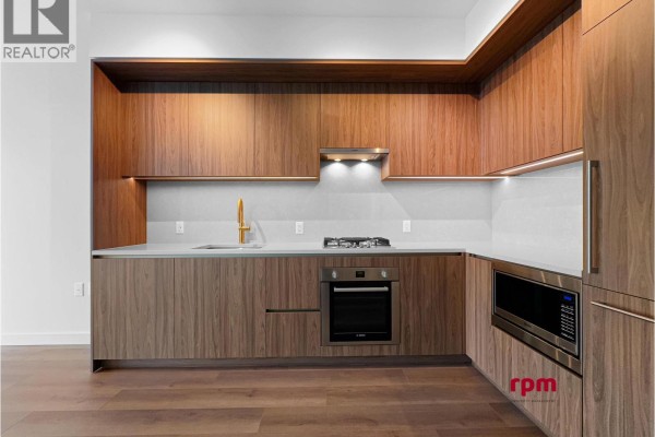 L-shaped kitchen with wood cabinets, grey backsplash, stainless steel oven and microwave. - 4xx 5987 Wilson Avenue, Burnaby