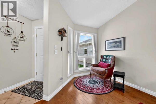 Corner of an entryway with a bay window, a plush armchair, and hardwood floors. - 5, 1200 Milt Ford Lane, Carstairs