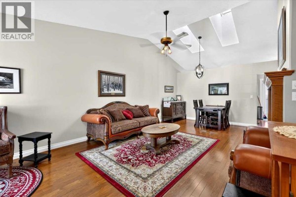 Living and dining area with vaulted ceiling, skylights, furniture, and hardwood floors. - 5, 1200 Milt Ford Lane, Carstairs