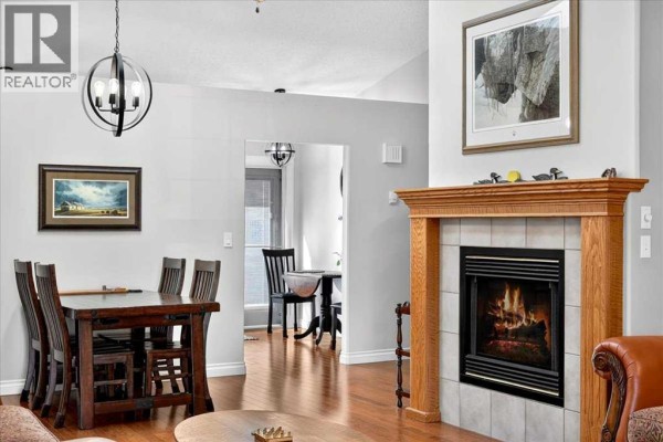 Dining table and chairs near a wooden fireplace with a gas insert and a framed artwork. - 5, 1200 Milt Ford Lane, Carstairs