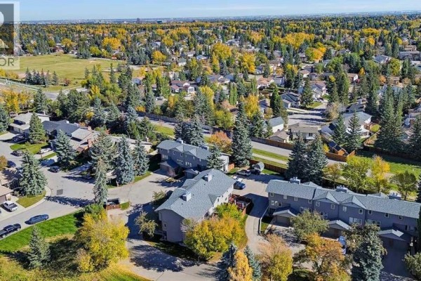 Aerial view of a residential neighborhood with townhouses and surrounding parkland. - 5, 64 Woodacres Crescent Sw, Calgary