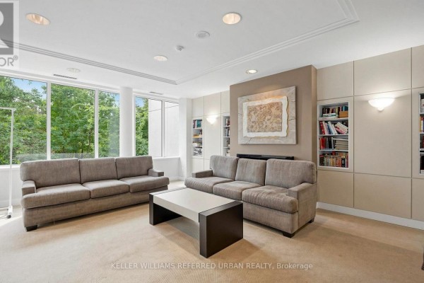 Common room with two grey sofas, a white coffee table, and built-in bookshelves. - 5 - 1 Watergarden Way, Toronto