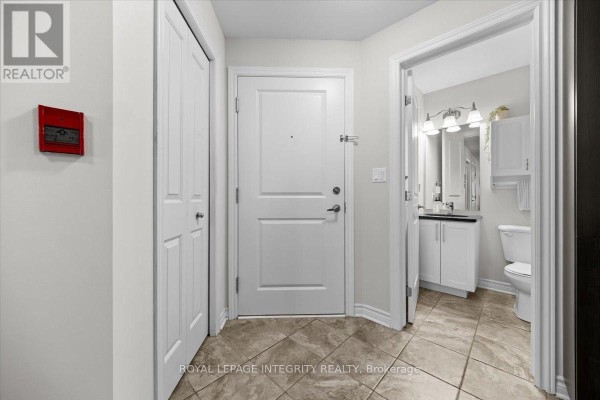 Apartment entryway with a white door, two closets, and an open bathroom door. - 5 - 100 Prestige Circle, Ottawa