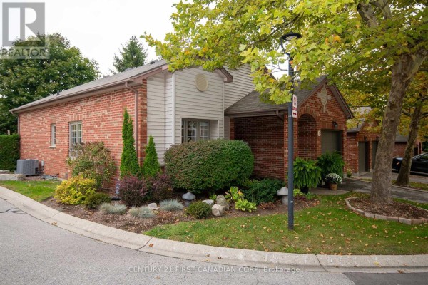 Side view of a townhouse showing red brick and beige siding with landscaping. - 5 - 1100 Byron Baseline Road, London South