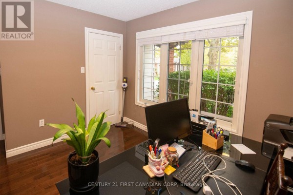 A home office with a desk, computer, and window overlooking the exterior. - 5 - 1100 Byron Baseline Road, London South